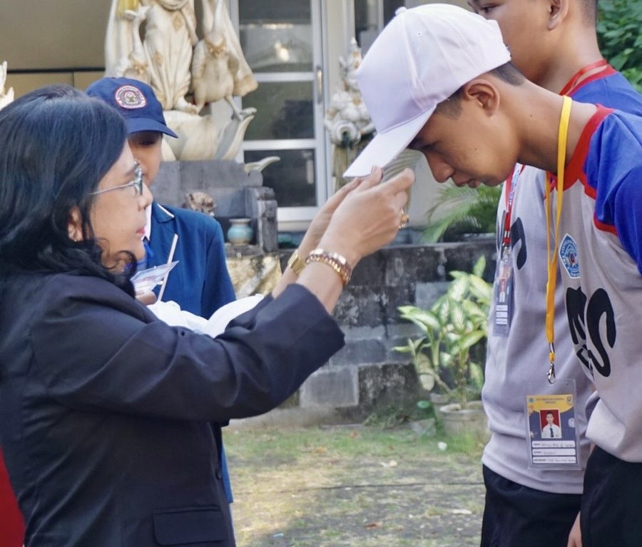 Bendahara Perdiknas Wayan Sri Maitri, SE., MM, memasang topi bagi murid baru.